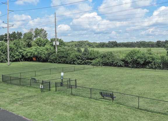 A green field with a fence and a bench.