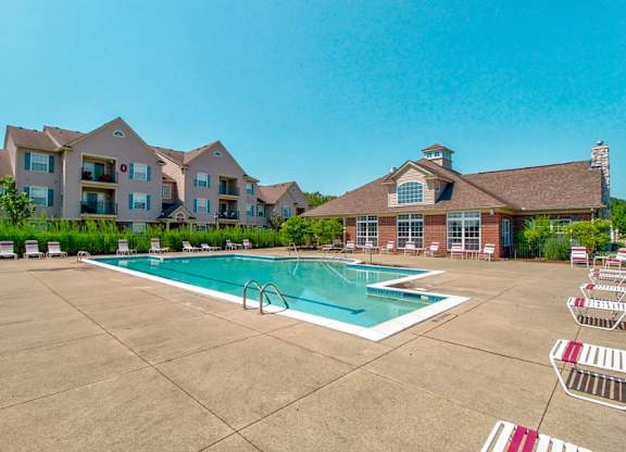 A large swimming pool in front of a building with a red and white striped pool ladder.