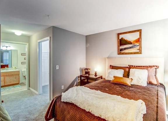 A bedroom with a large bed and a painting on the wall.