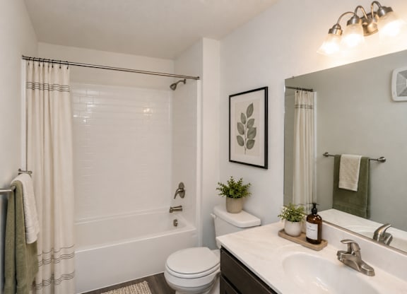 A white bathroom with a toilet, sink, and shower.
