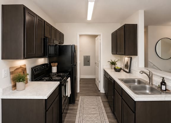 A kitchen with dark brown cabinets and a black stove top oven.