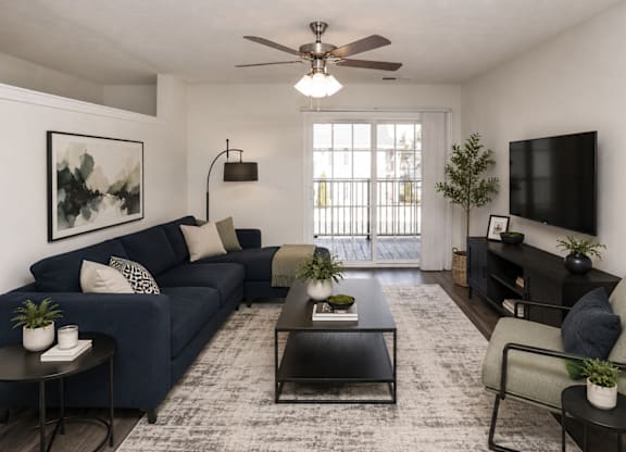 A living room with a dark blue couch, a black coffee table, and a flat screen TV mounted on the wall.