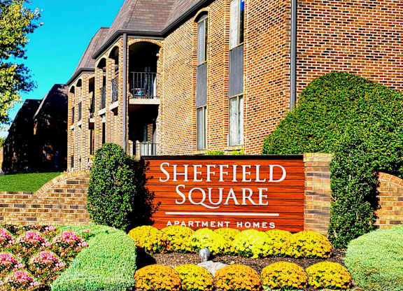 A sign for Sheffield Square Apartment Homes is in front of a brick building.