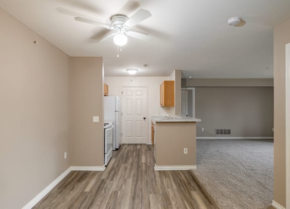 A room with a ceiling fan and a kitchenette.