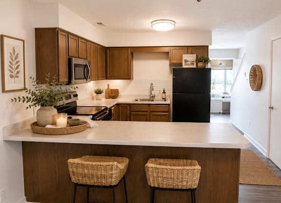 A kitchen with a bar and two stools.