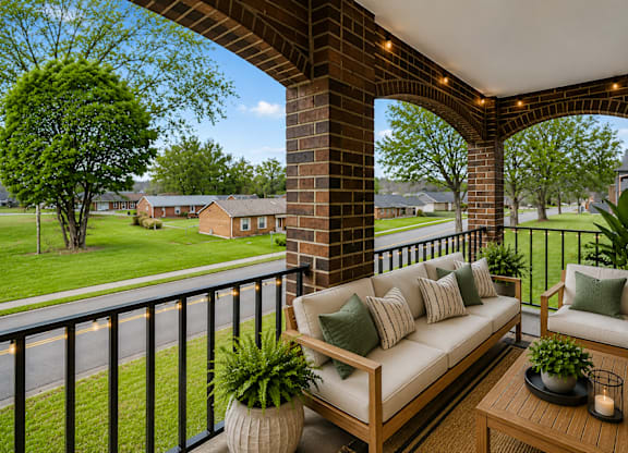 A balcony with a couch, pillows, and plants.