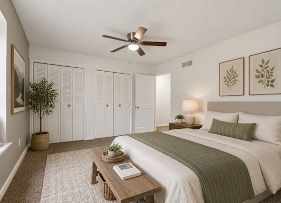 A bedroom with a bed, a ceiling fan, and a plant.