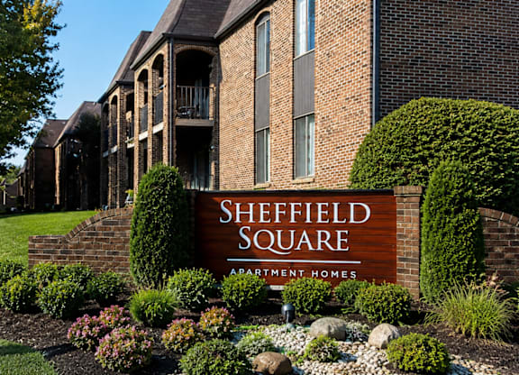 A sign for Sheffield Square is in front of a brick building.