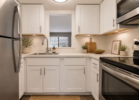 A kitchen with white cabinets and a stainless steel refrigerator.