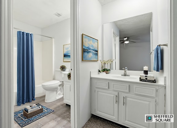 A bathroom with a white toilet and a white sink with a blue curtain.
