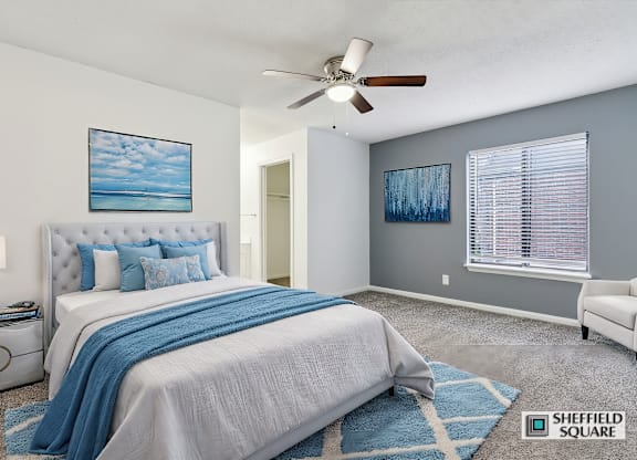A bedroom with a large bed and a ceiling fan.