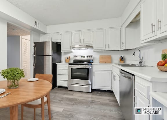 A kitchen with a table and chairs in the foreground and a refrigerator, oven, and sink in the background.