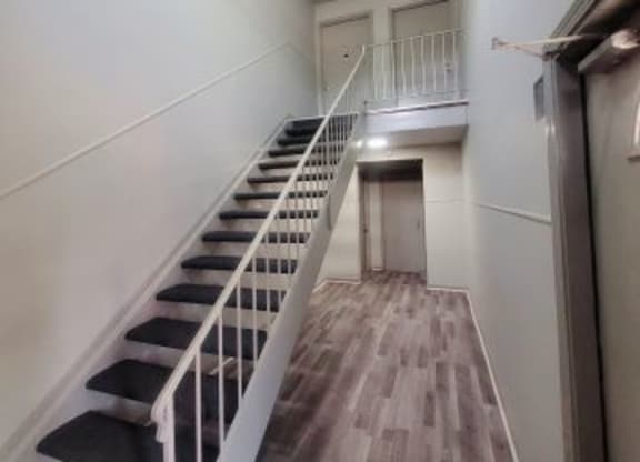 Interior of Woodhaven Park apartment building with hardwood-style flooring and black stairs leading to the second level.  