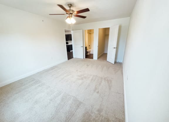 an empty living room with white walls and a ceiling fan