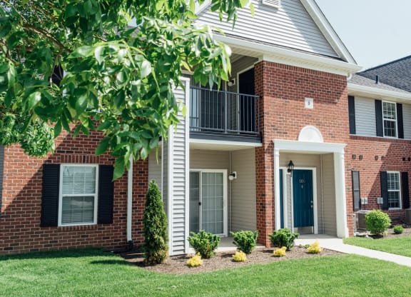 the outlook of a brick house with a balcony and a yard