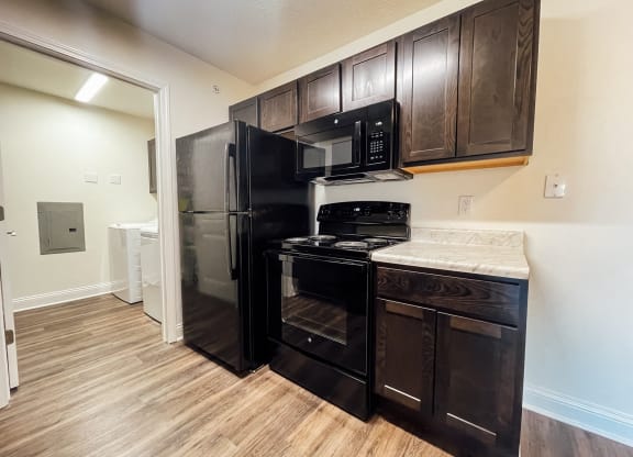 a kitchen with black appliances and wood flooring in a home