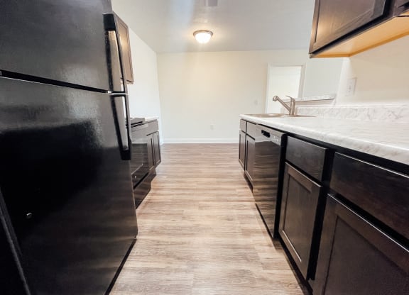an empty kitchen with black appliances and a white counter top