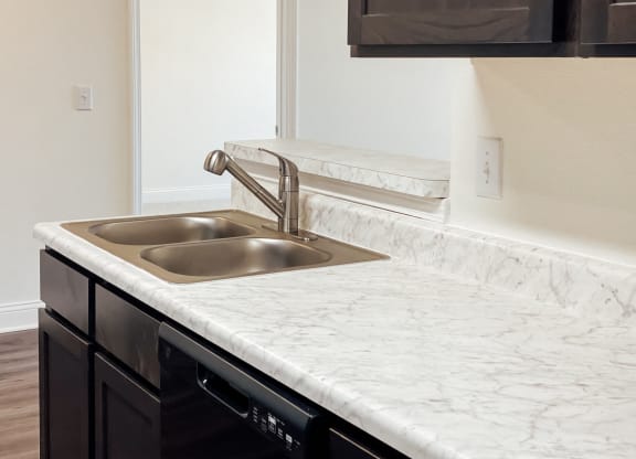 a kitchen with marble counter tops and a stainless steel sink