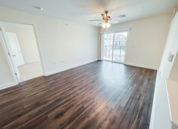 an empty living room with wooden floors and a ceiling fan