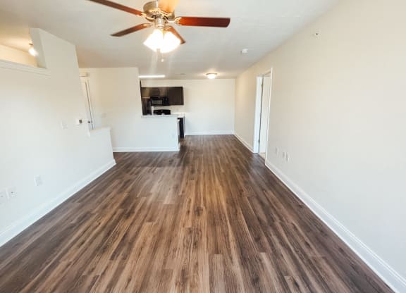 an empty living room with a ceiling fan and wood flooring