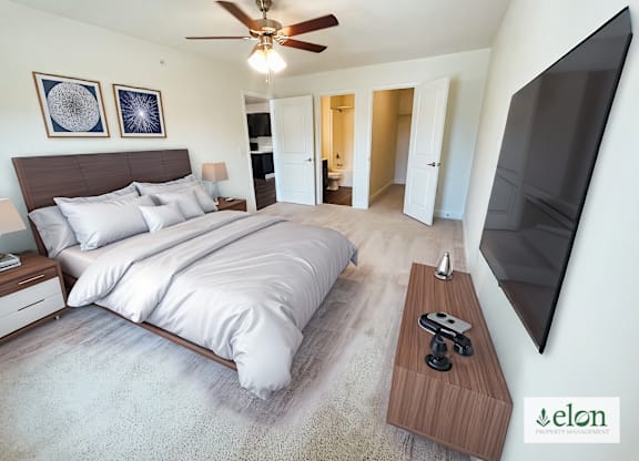 A bedroom with a large bed and a flat screen TV mounted on the wall.