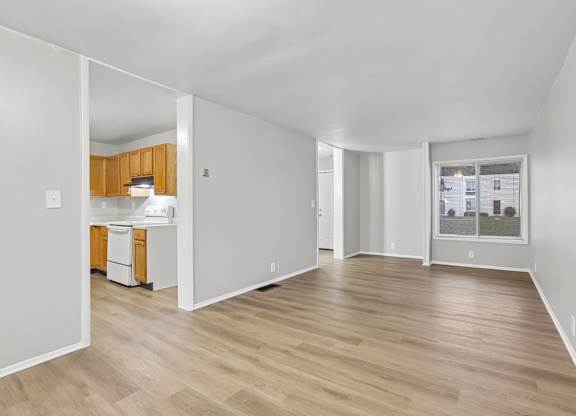 A spacious room with wooden flooring and white walls.