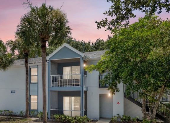 a building with two palm trees in front of it at Aqua Bay Apartments in Naples, FL 34116