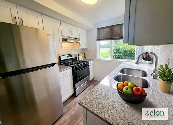 A modern kitchen with a stainless steel refrigerator and a bowl of fruit on the counter.