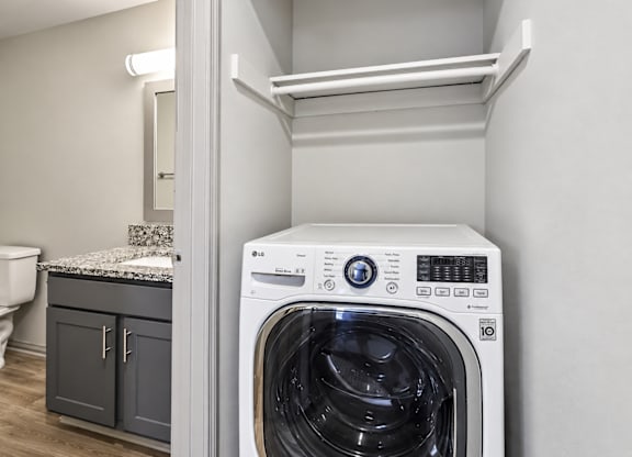A white front loading washing machine in a laundry room.