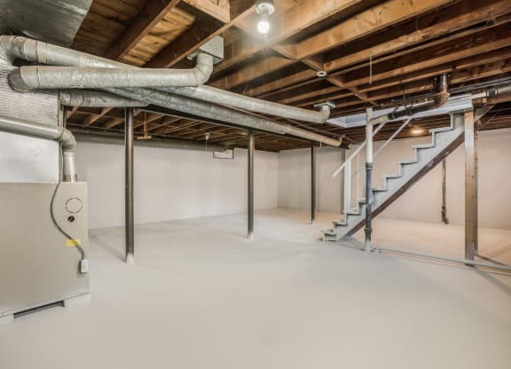 a large basement with pipes and a staircase in it