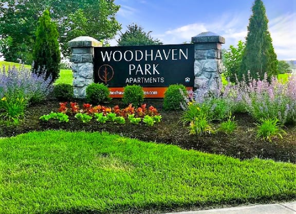 a sign for woodhaven park in front of a garden
