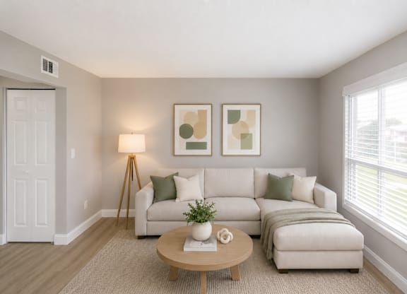 A living room with a white couch, a wooden coffee table, and two framed artworks on the wall.