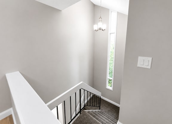 A staircase with a white railing and a chandelier hanging from the ceiling.