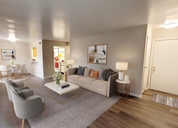 Spacious living room with a couch, coffee table, and 2 chairs next to the kitchen and dining area.  