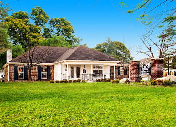 Exterior of the resident clubhouse with a large grassy area and several trees. 