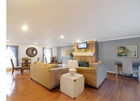 Spacious living room with hardwood floors, a fireplace, 2 windows, and numerous seating options.