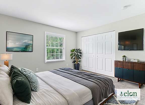 A bedroom with a large bed and a painting on the wall.