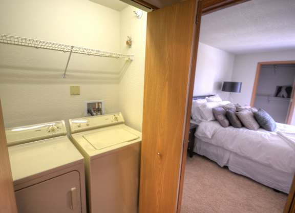 a bedroom with a washer and dryer next to a bed