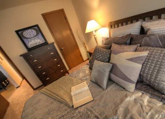 a bedroom with a bed with pillows and a dresser