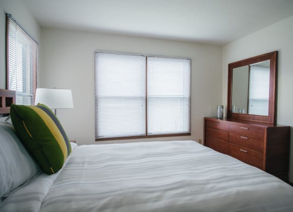 a bedroom with a bed and a dresser and two windows
