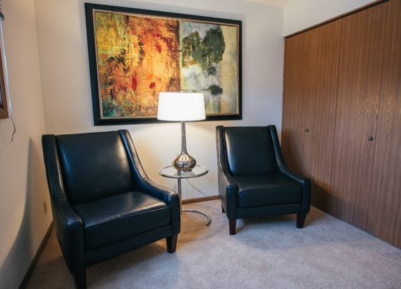 a living room with two black chairs and a painting on the wall