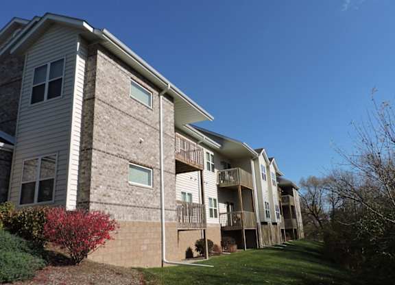 an apartment building with a grass yard and a blue sky