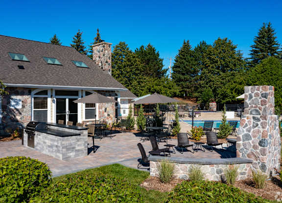 Clubhouse with a stone chimney and a patio with chairs and a table.