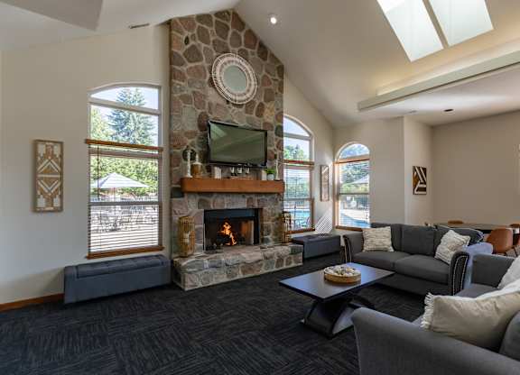 A living room with a stone fireplace and a flat screen TV.