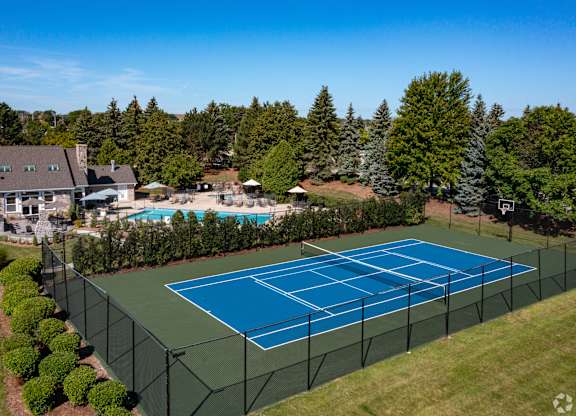 A tennis court surrounded by a fence and trees.