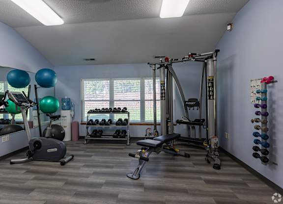 A gym with a variety of equipment including weights, a treadmill, and a bench press.