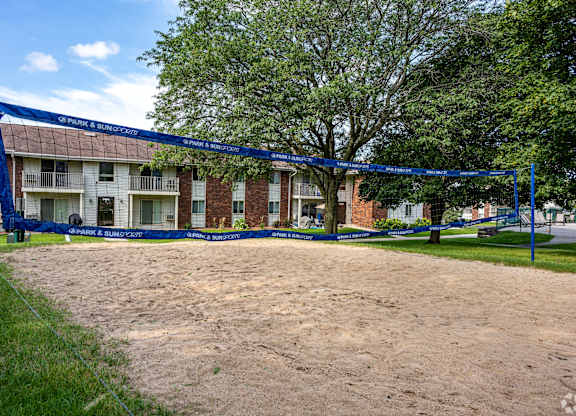 A volleyball net is set up in the sand in front of a brick building.