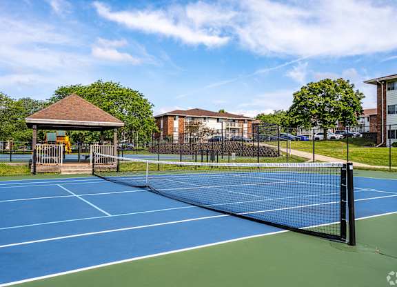 A tennis court with a blue surface and a black fence.