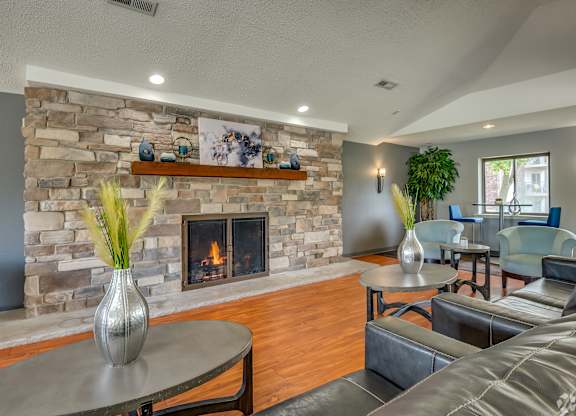 A living room with a stone fireplace and a grey sofa.