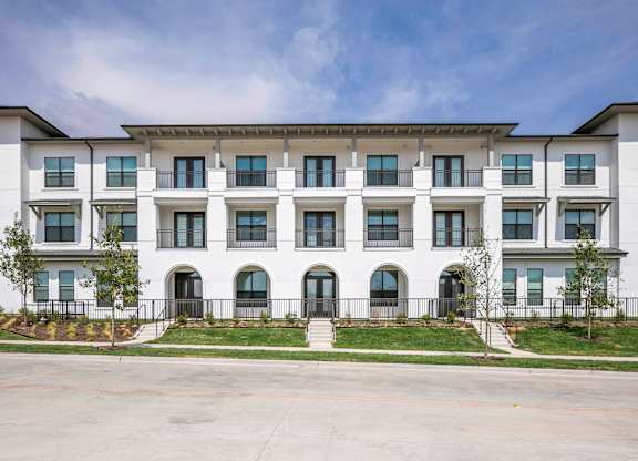 a large white building with a blue sky in the background lots of windows and arched entryways